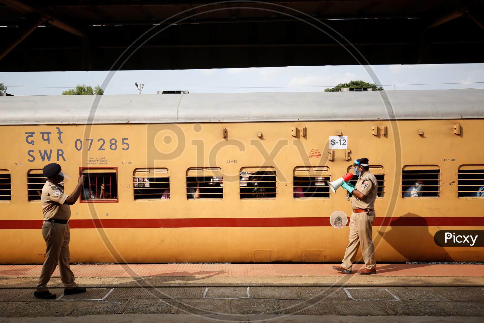 A Railway Protection Force (RPF) personnel uses a megaphone to make a public safety announcement to people travelling to Danapur, Bihar in a special train arranged by the government to repatriate migrant workers at the Chikkabanavara Junction Railway Station on the outskirts of Bangalore, India.