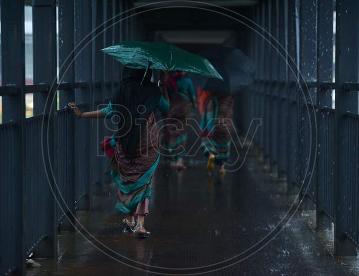 women walk on a foot over bridge as it rains heavily