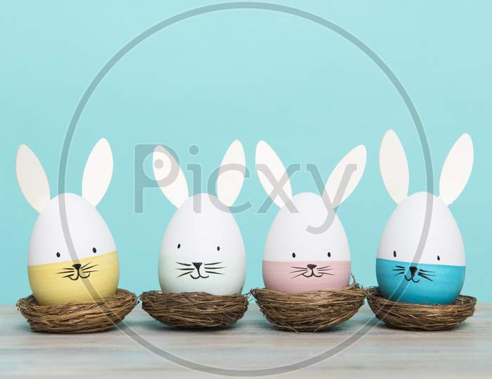 Easter Eggs With Bunny Faces In Nest On A Blue Background