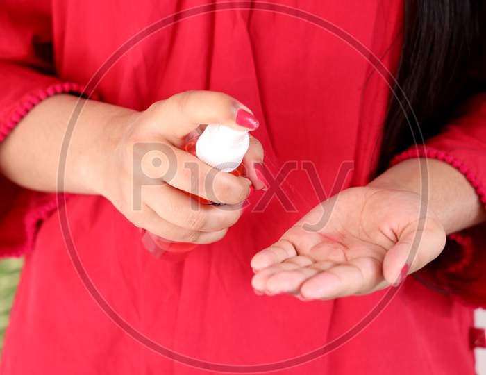 A young girl sanitizing her hands