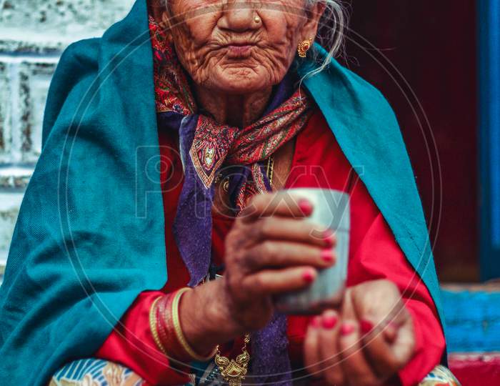 New Delhi, Delhi/ India- May 31 2020:A Portrait Of An Old Lady Wearing Shawl With A Steel Glass In Her Hand.