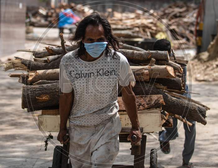 A Worker Carries Wood For The Funeral Of Covid-19 Victim At Nigambodh  Crematorium In New Delhi, India On May 31, 2020.
