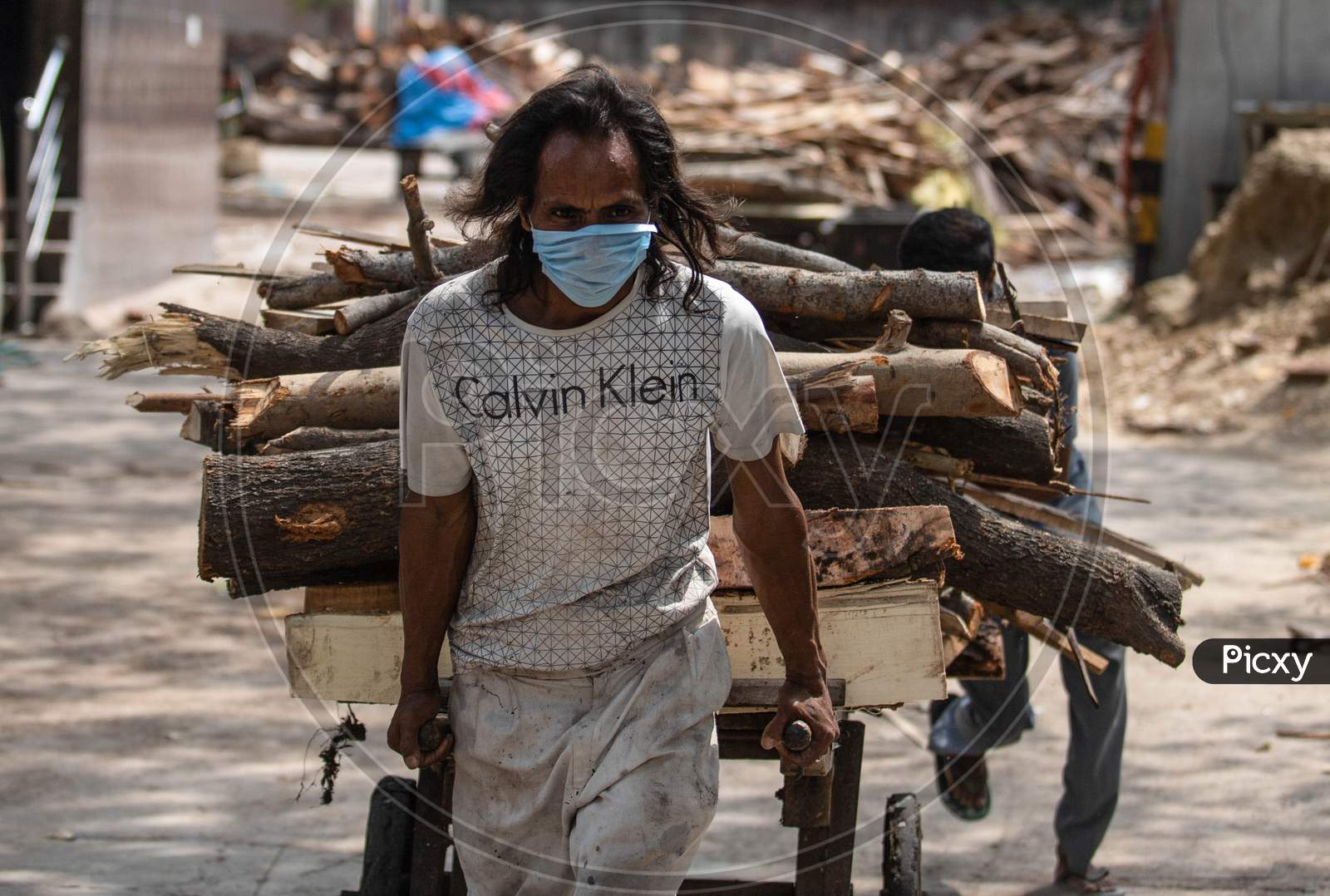 A Worker Carries Wood For The Funeral Of Covid-19 Victim At Nigambodh  Crematorium In New Delhi, India On May 31, 2020.