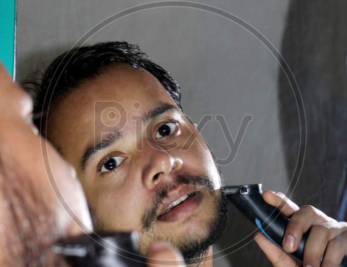 Young Man Shaving Beard With Trimmer
