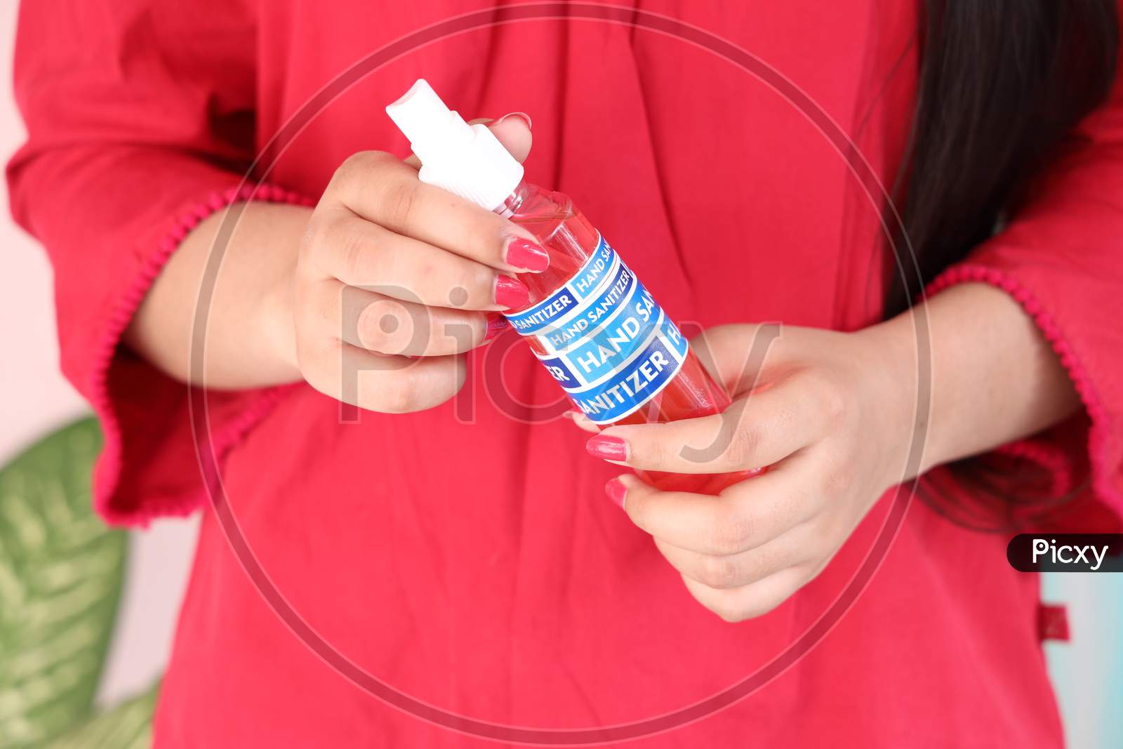 Young girl holding hand sanitizing liquid bottle to sanitize her hands
