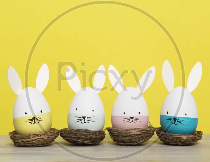 Easter Eggs With Bunny Faces In Nest On A Yellow Background
