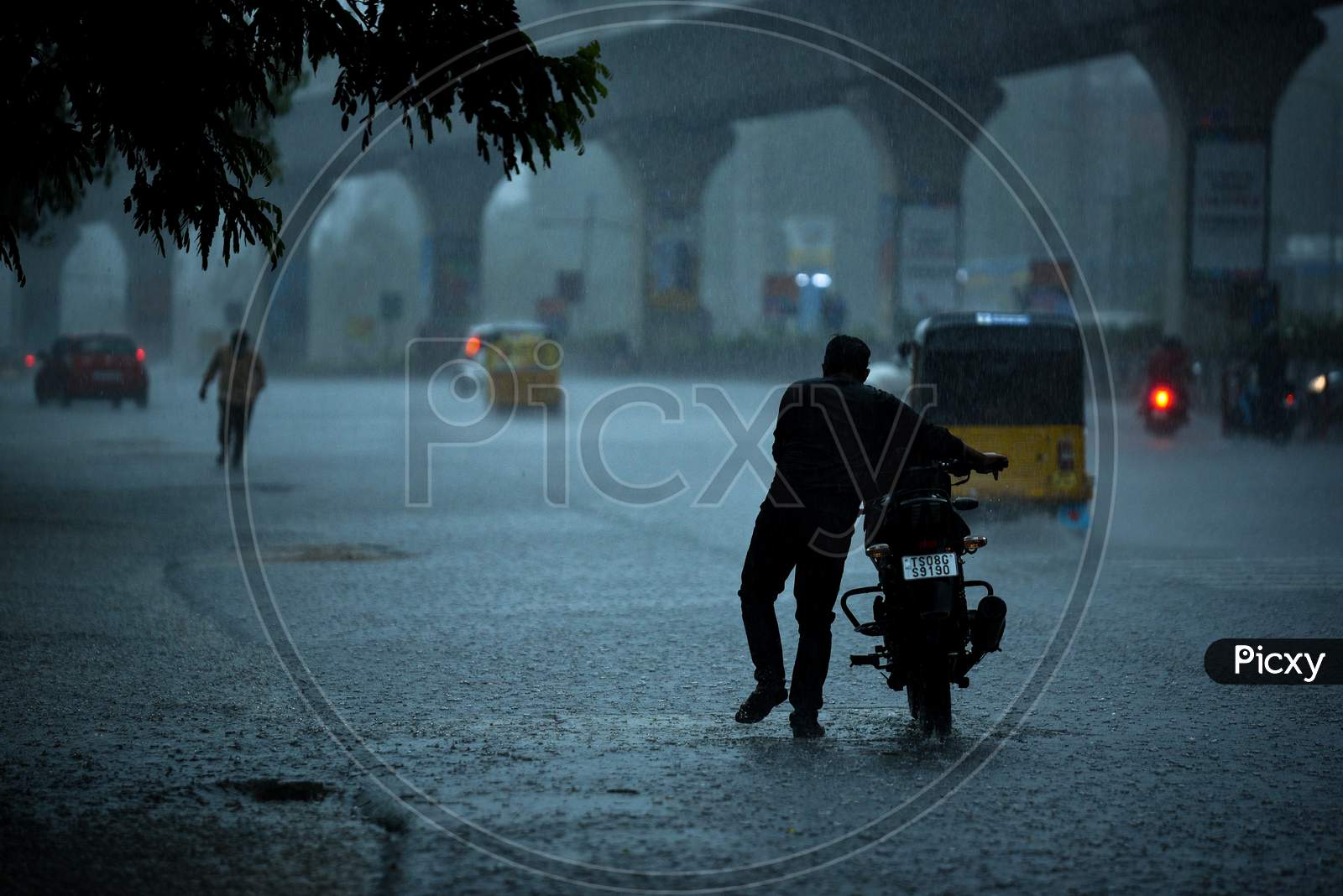 a man pushes his bike amid heavy rain, may 31, 2020