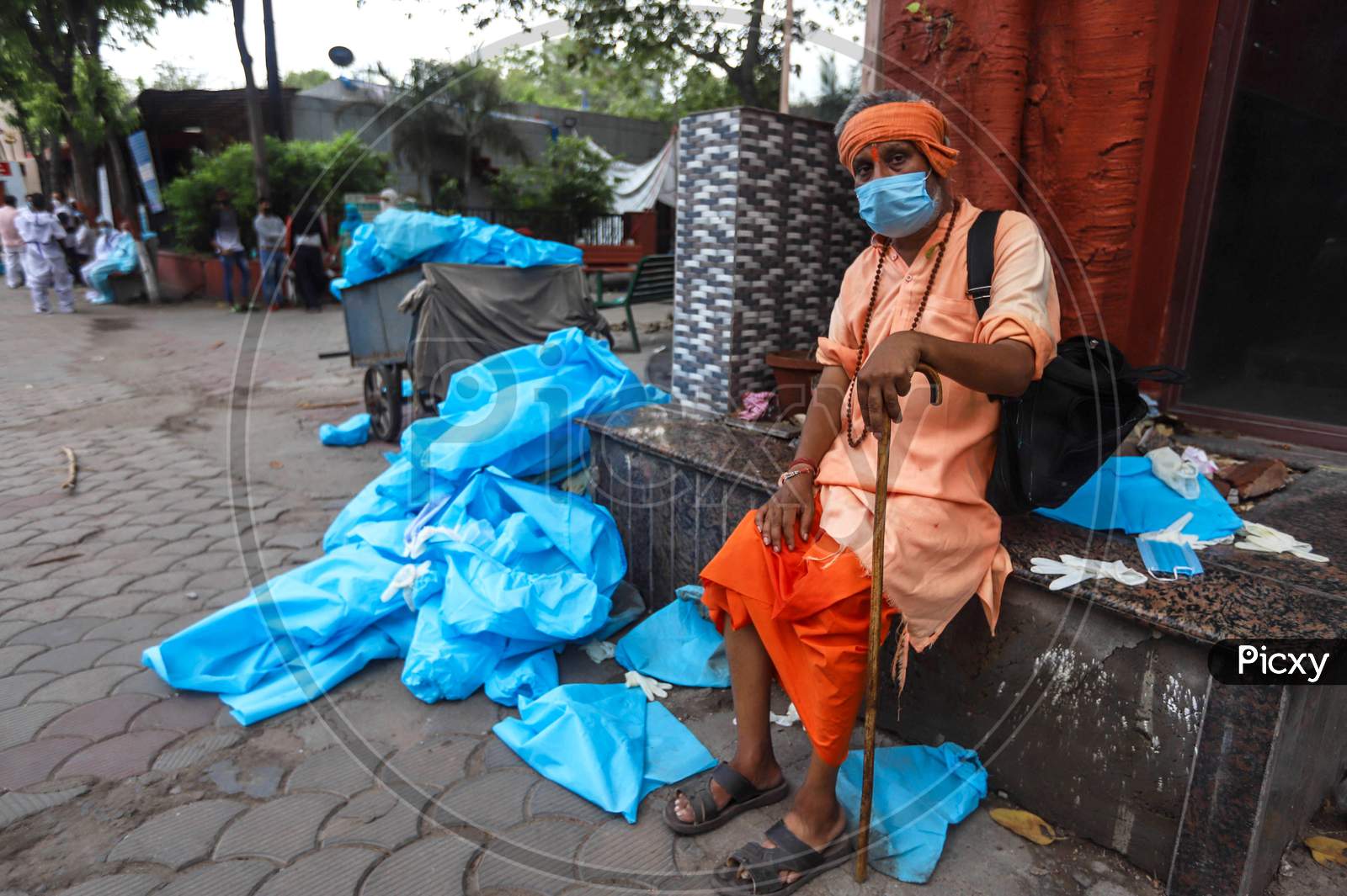 A Man Sits Next To The  Discarded Latex Gloves, Surgical Masks And Ppe Suits Lie after the cremation of a Deceased Covid-19 patient At  Nigambodh Crematorium In New Delhi, India On May 31, 2020.