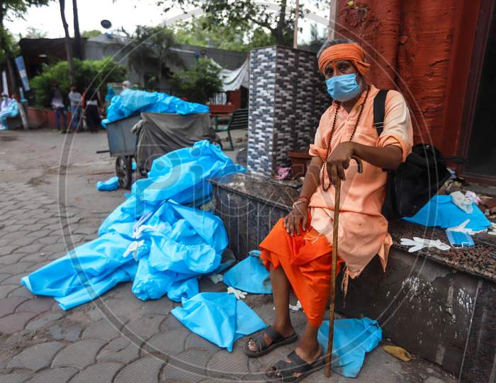 A Man Sits Next To The  Discarded Latex Gloves, Surgical Masks And Ppe Suits Lie after the cremation of a Deceased Covid-19 patient At  Nigambodh Crematorium In New Delhi, India On May 31, 2020.