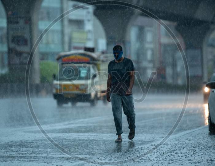 a masked man walks on the road as it rains heavily during the nationwide lockdown amid fears of coronavirus, may 31, 2020, Hyderabad