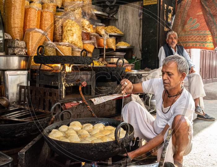 A man preparing kachori at a shop and snacks being sold at the shop in jaipur, march 2019