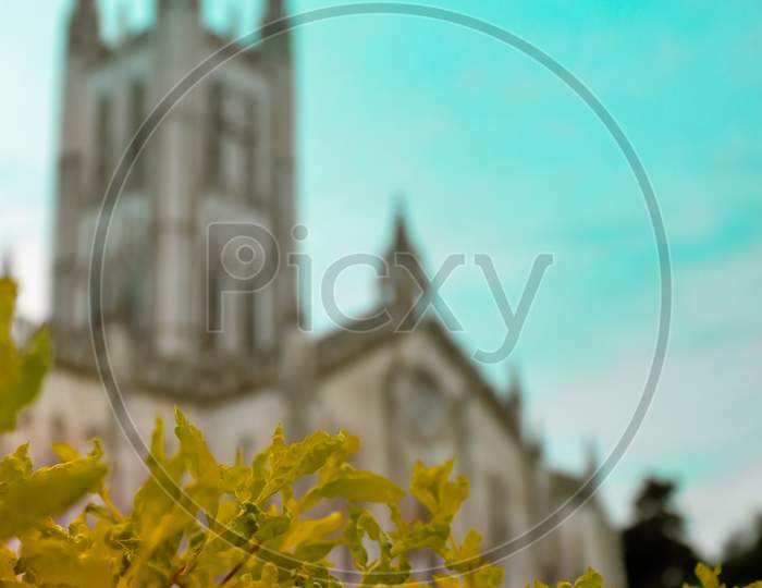 A brunch of colorful leaves in front of the church with blurred background and blue sky.