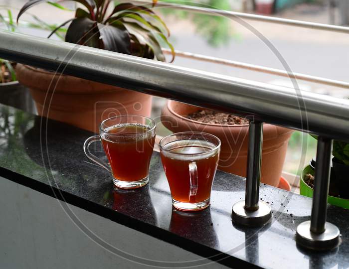 Two glasses of herbal tea on a balcony ledge