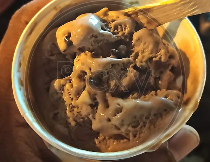 Small Scoop Of Chocolate Ice Cream With Wooden Ice Cream Spoon On It.