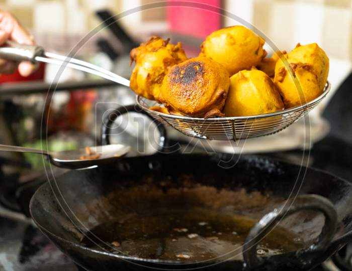Shallow Depth Of Field Shot Of Vada Potatoes Wrapped In Flour Being Taken Out Of Hot Oil After Deep Frying