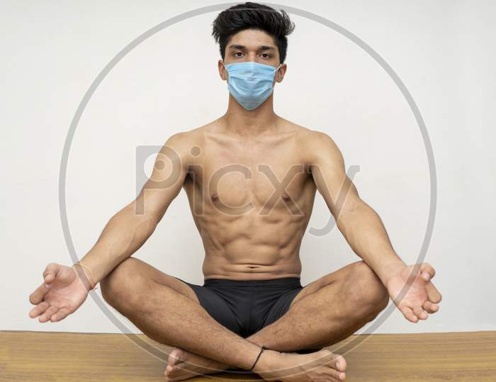 Young Handsome Shredded Boy Doing Yoga Wearing A Blue Mask