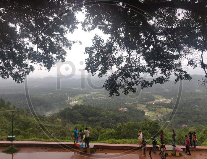 July 6, 2019- Karnataka, India: A Landscape View Of Raja'S Seat Park Filled With Fog In Coorg, Karnataka, India. People Spectating The View.