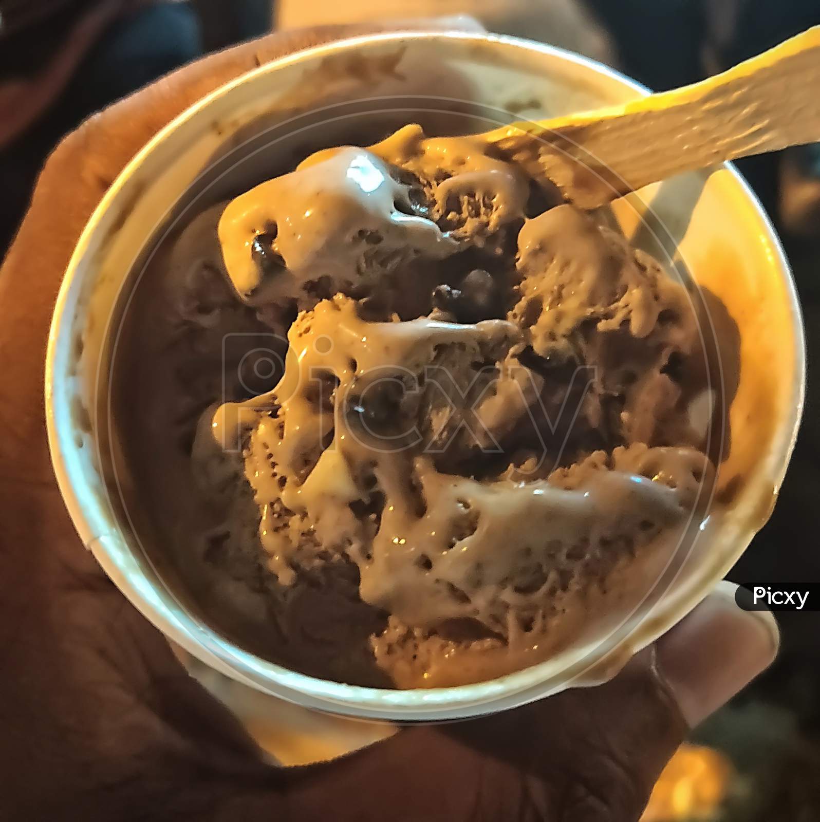 Small Scoop Of Chocolate Ice Cream With Wooden Ice Cream Spoon On It.