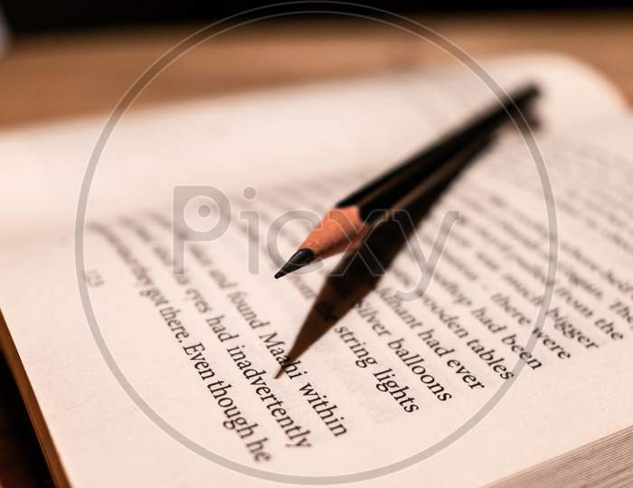 A wooden pencil lying on a page of a opened book