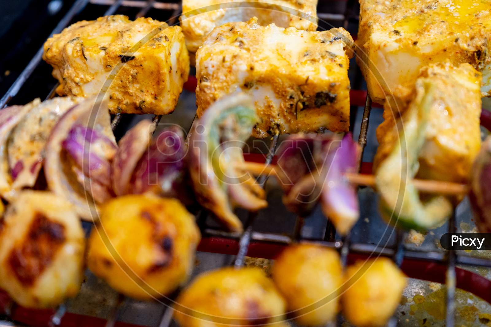 Shallow Depth Of Feild Shot Of Cottage Cheese Paneer Vegetables Onions, Mushrooms And Potatoes Being Grilled On An Electric Grill At Home