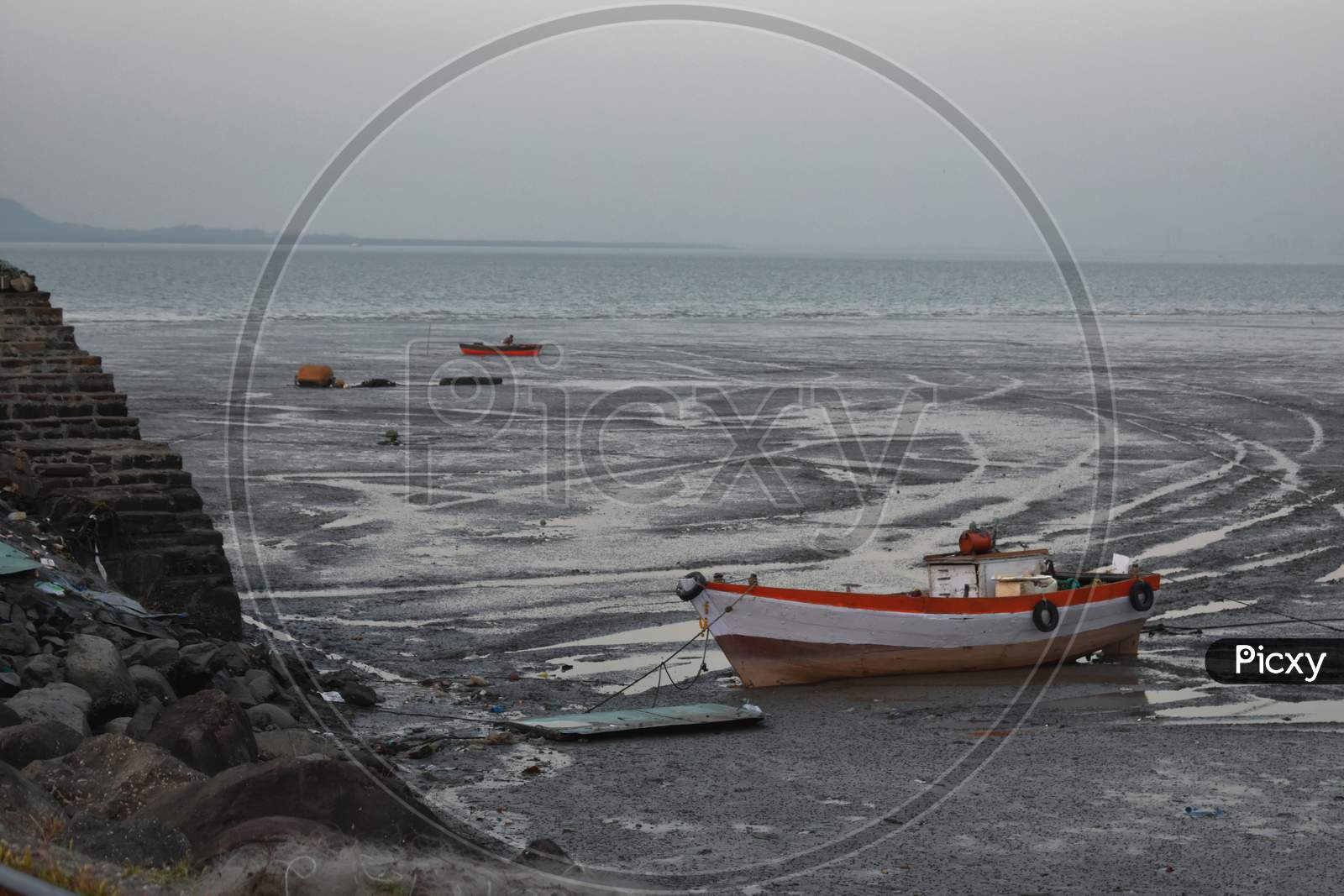 A Fishing Boat Standing During The Low Tide Near A Ocean.