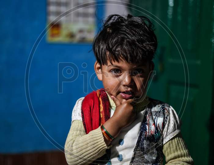 Almora, Uttrakhand / India - June 10 2020: A Portrait Of A Little Girl Holding Her Chin, Living In A Very Dull And Dark Room.