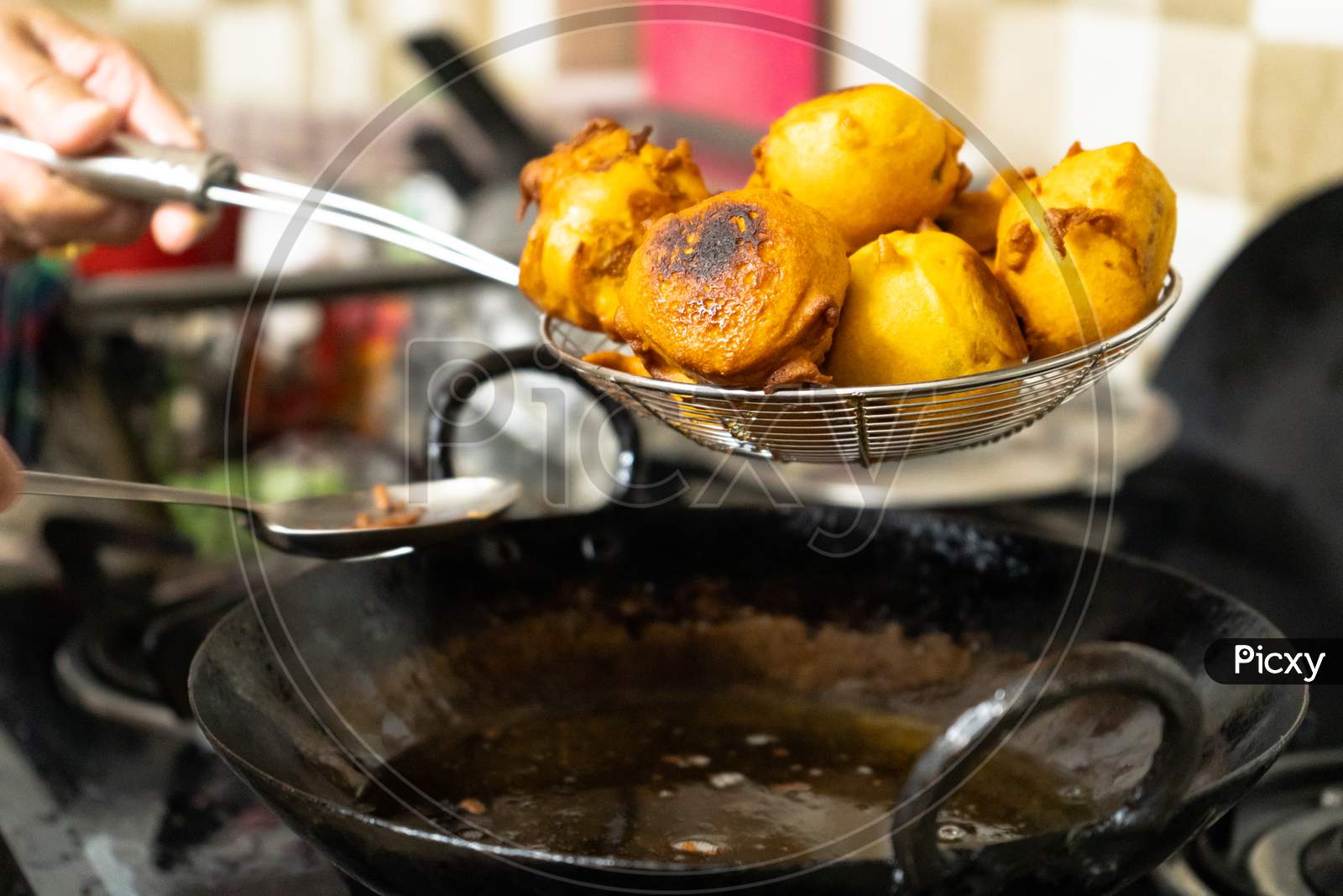Shallow Depth Of Field Shot Of Vada Potatoes Wrapped In Flour Being Taken Out Of Hot Oil After Deep Frying