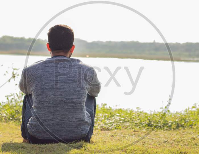 A Lonely Man Sitting In Front Of The Lake In Sunny Day - Concept Of Loneliness, Break Up,Single And Alone.