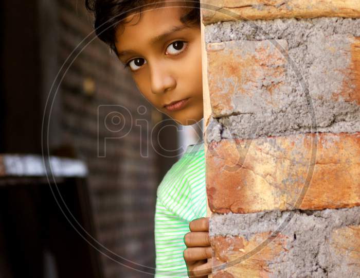 Portrait of a Rural Kid behind a Brick Wall