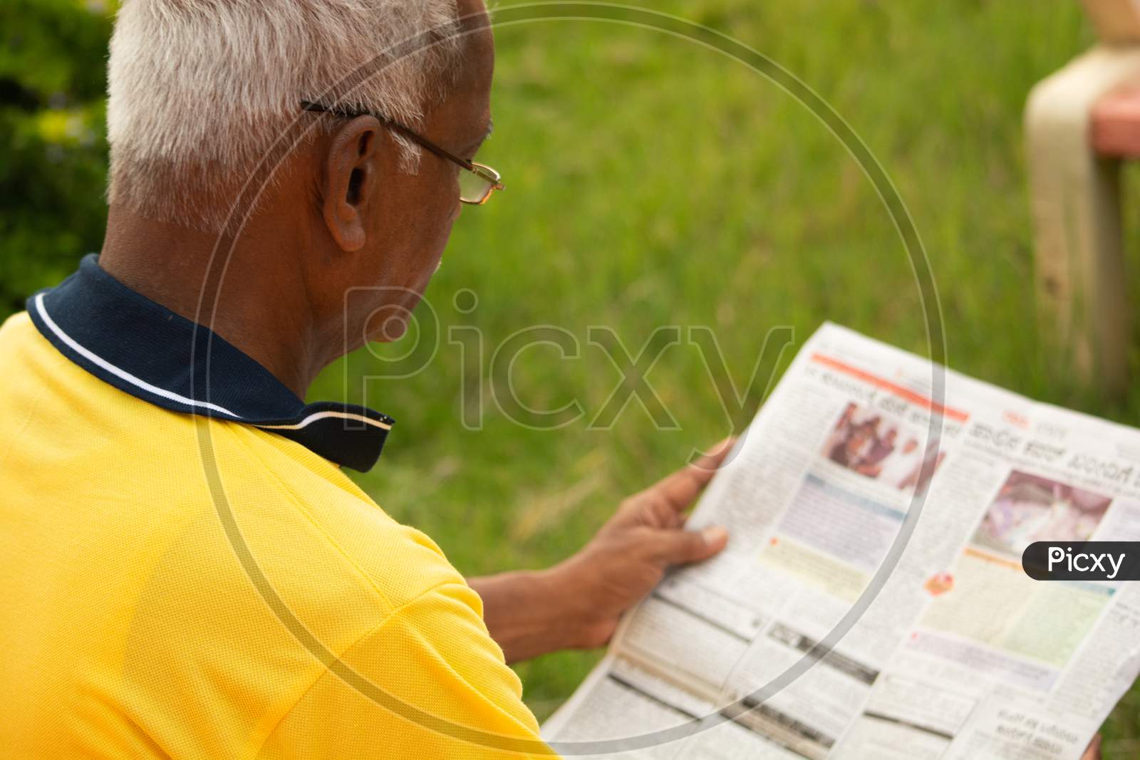 An old man or Elderly man reading a newspaper at outdoors