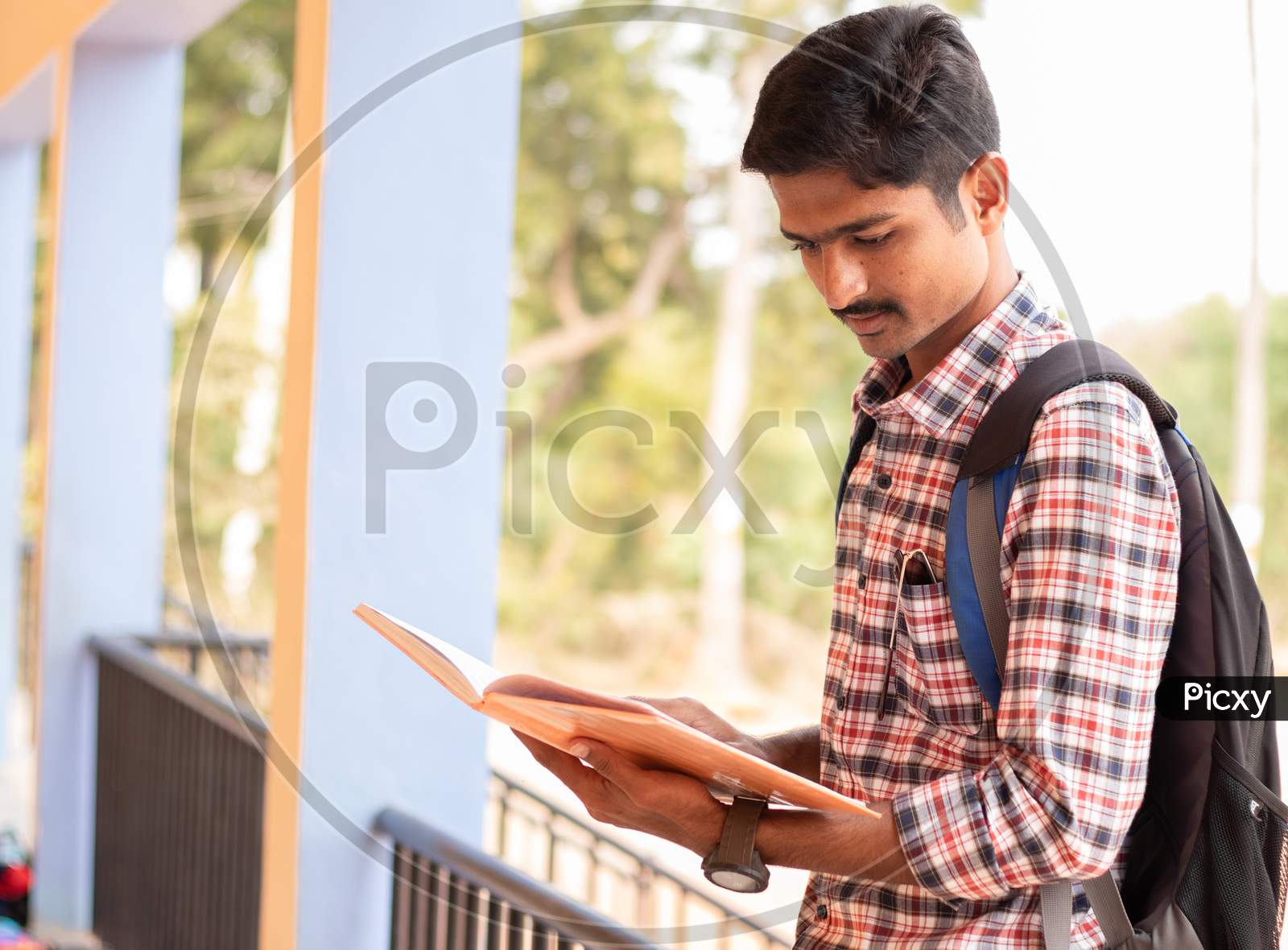 A Student studying by Looking Into Books At College - Education, Learning Student, People Concept