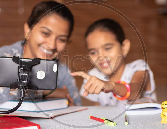 Young Girl Teaching Her Sister At Home - Concept Of Online Homeschooling During Coronavirus Or Covid-19 Lockdown Pandemic