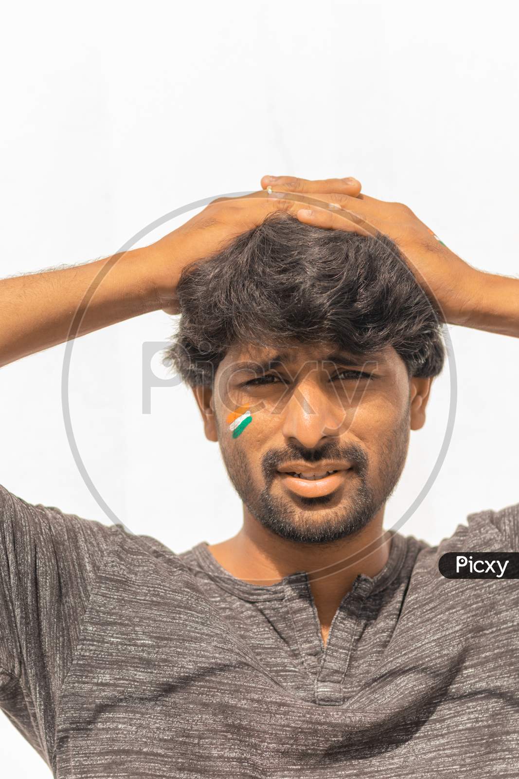 Portrait Of Curious Or Tense Young Indian Male Cricket Sports Fan Painted Indian Flag On His Face.