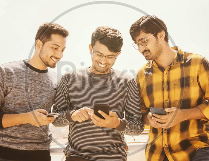 Group Of Young People Watching Mobile Phone On Terrace And Laughing - Friends Using Mobile Phone Againt The Sunlight - Millennials On Technology, Social Media And Internet Concept - Filter Image.