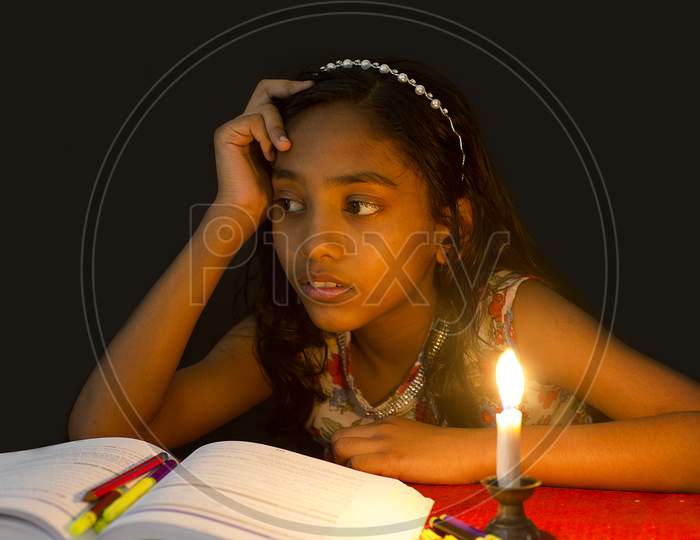 Portrait of a Young Indian School Kid with A Book and Candle in the foreground