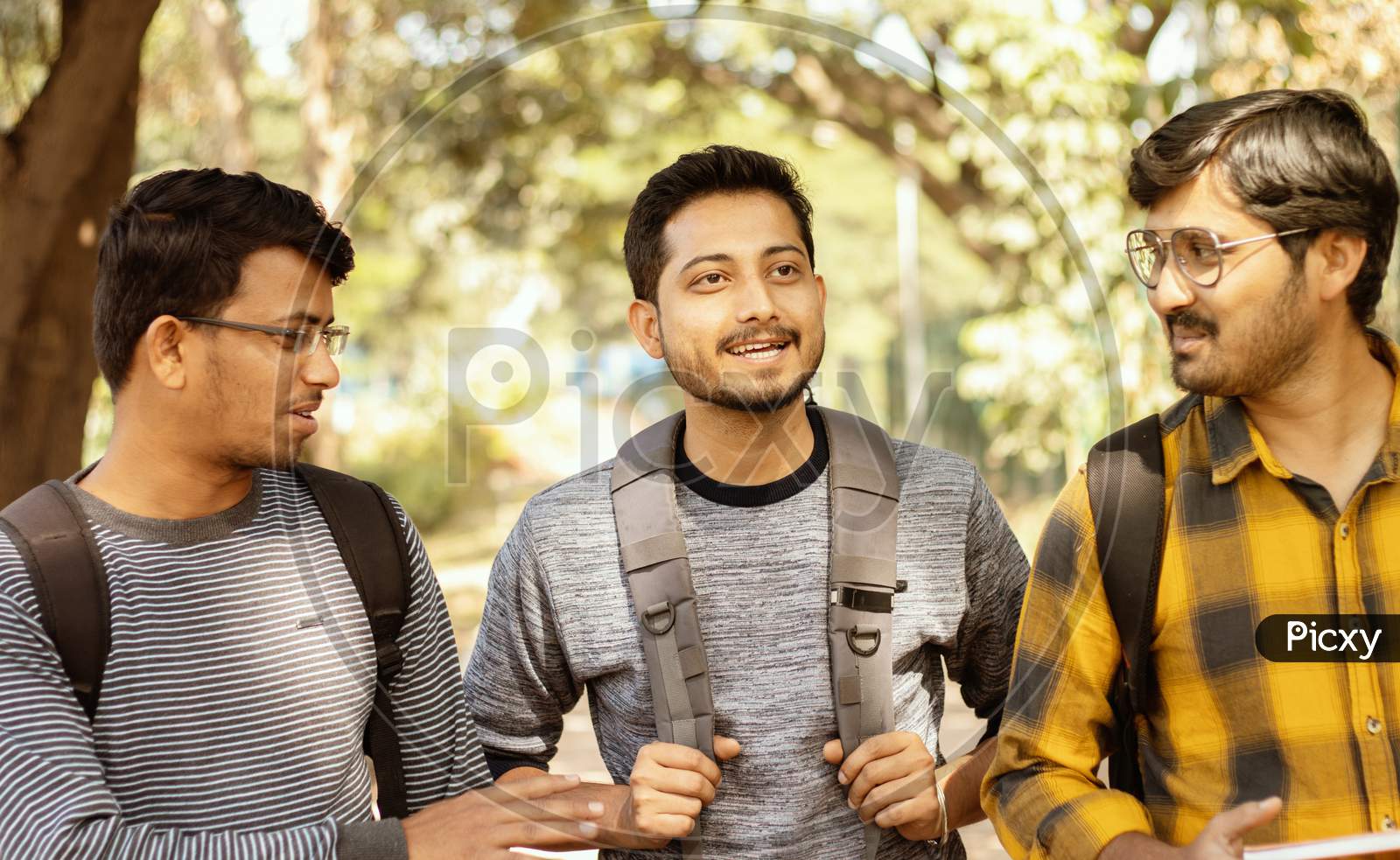 Three Students Talking Or Socializing At University Campus - Friends Having Fun And Conversation At College - Concept Of Happy Friendship, College Days And Student Life.