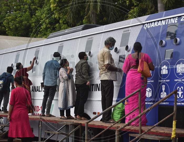 Passengers wait at a mobile swab collection bus, after their arrival at Vijayawada by Konark Express train, from a mobile swab collection bus, at Vijayawada Railway Station.