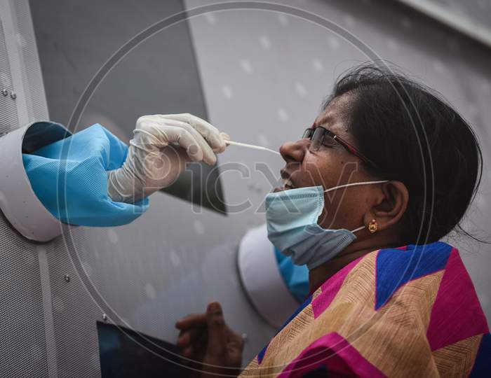 A healthcare worker collects a swab sample of a passenger who arrived at Vijayawada by Konark Express train, from a mobile swab collection bus, at Vijayawada Railway Station.