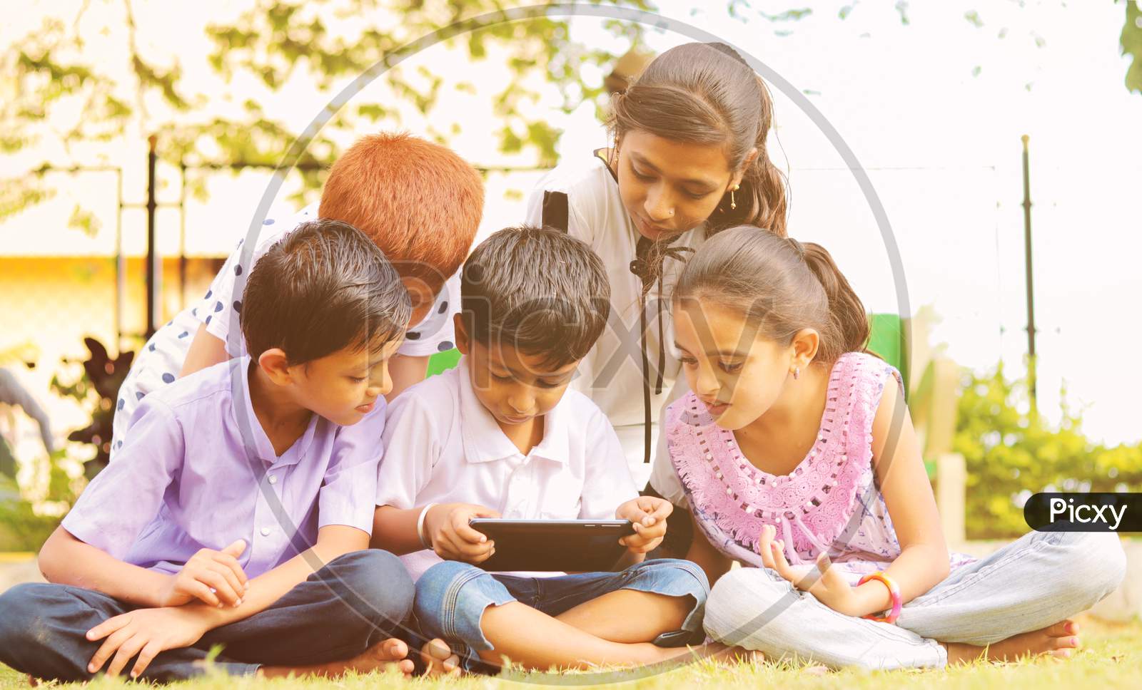 Group of Children using a Mobile or Smartphone in a Park or Outdoors