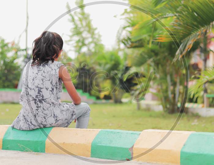 Back View of A Kid Sitting Alone in a Park