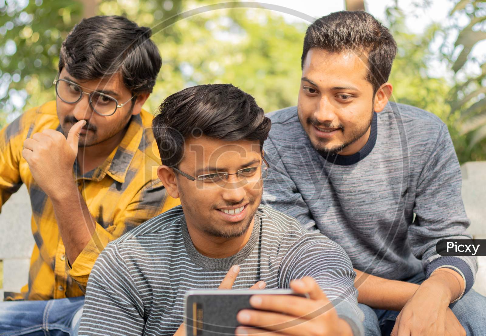 Group Of Happy Young College Students Using Mobile Phone At University Campus