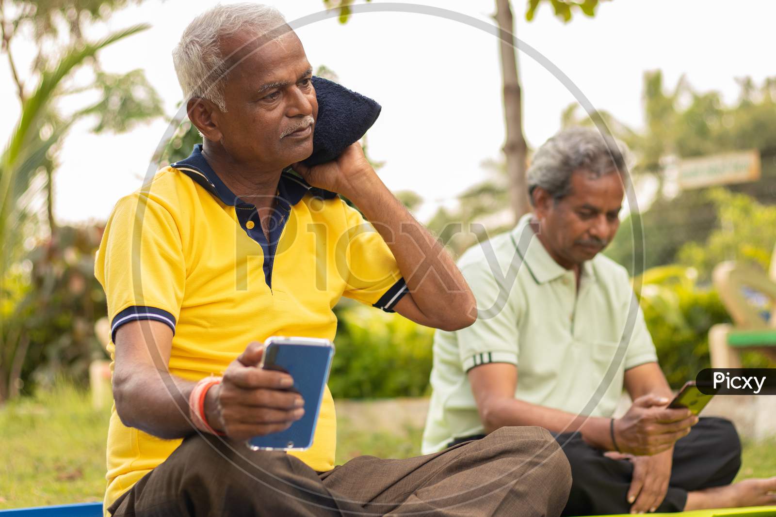 A couple of Elderly or Old Men's using Smartphone or Mobile Phone while doing Fitness Activity in a Park