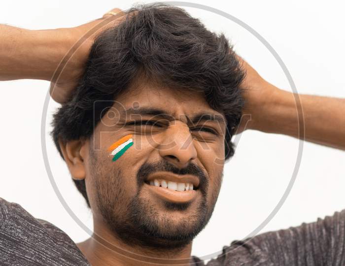 Closeup Shot, Sad Expression Of Male Indian Cricket Sport Fan With Painted Indian Flag On Face, Isolated Background.