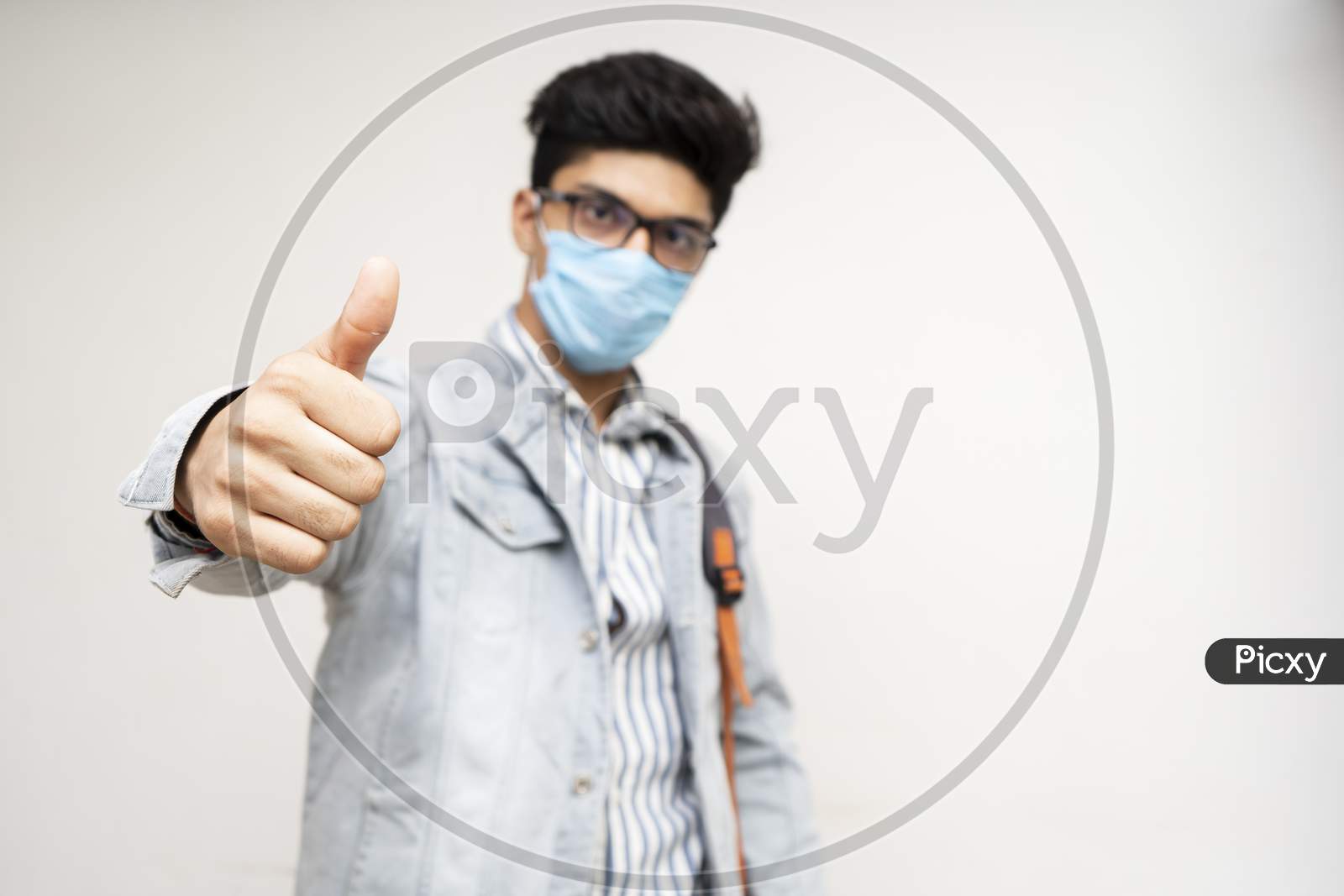 Young Handsome Asian College Student With Bag And Wearing Mask Showing Thumbs Up In The Camera.