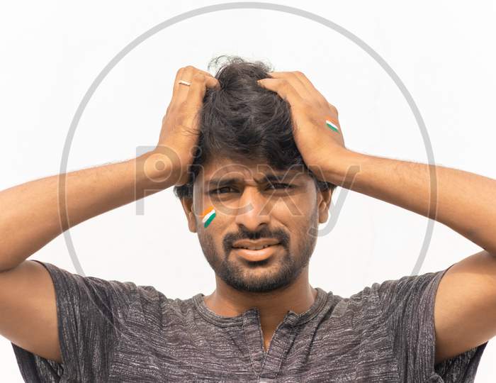 Portrait Of Curious Or Tense Young Indian Male Cricket Sports Fan Painted Indian Flag On His Face.