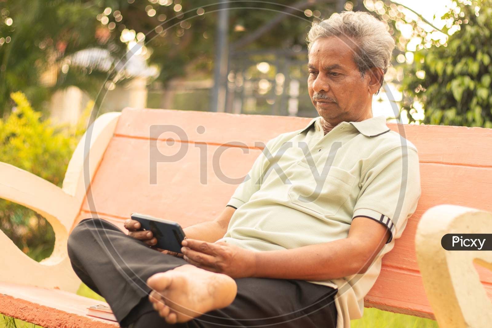 An old man or Elderly man using a mobile phone at the outdoors