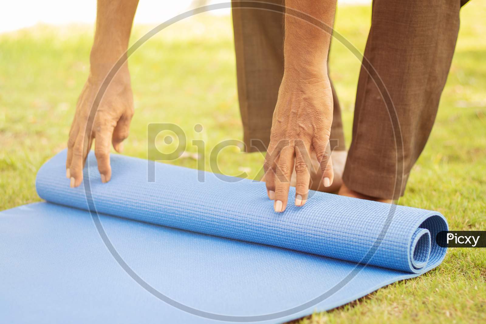 Close Up shot of A Elderly Man folding a Yoga Matt
