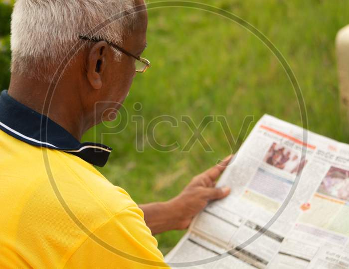 An old man or Elderly man reading a newspaper at outdoors