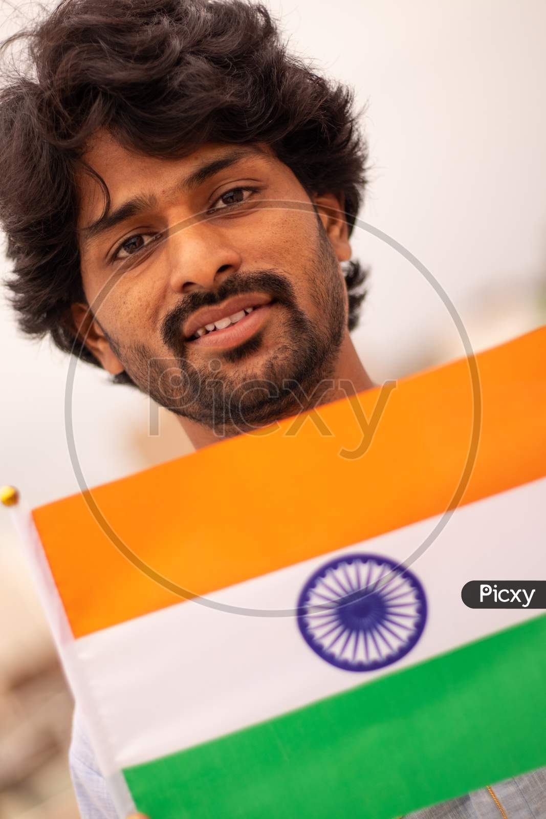 Portrait Of A Young Indian Man Holding Indian Flag In Traditional Indian Dress.