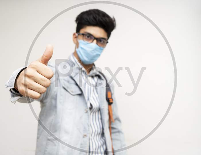 Young Handsome Asian College Student With Bag And Wearing Mask Showing Thumbs Up In The Camera.